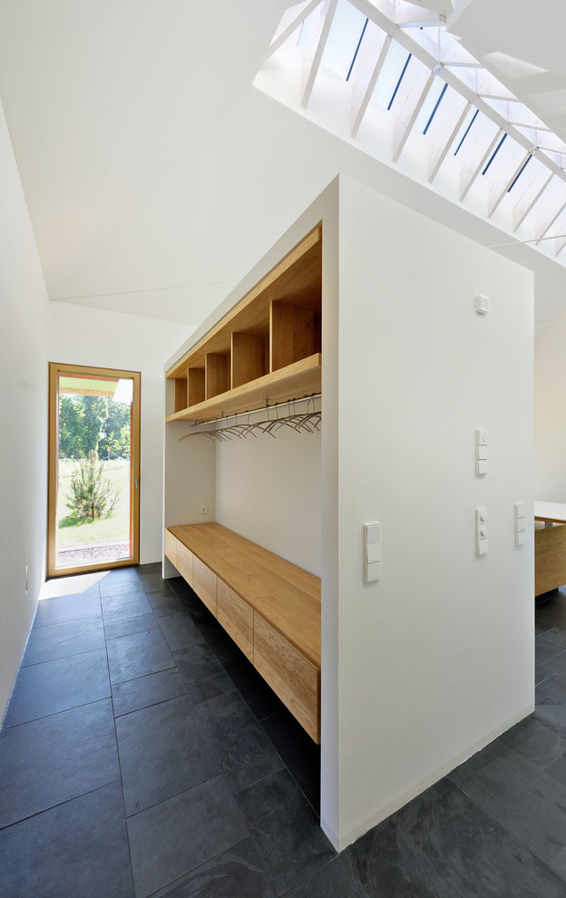 Medium sized contemporary boot room in Berlin with white walls, slate flooring, a single front door and a glass front door.