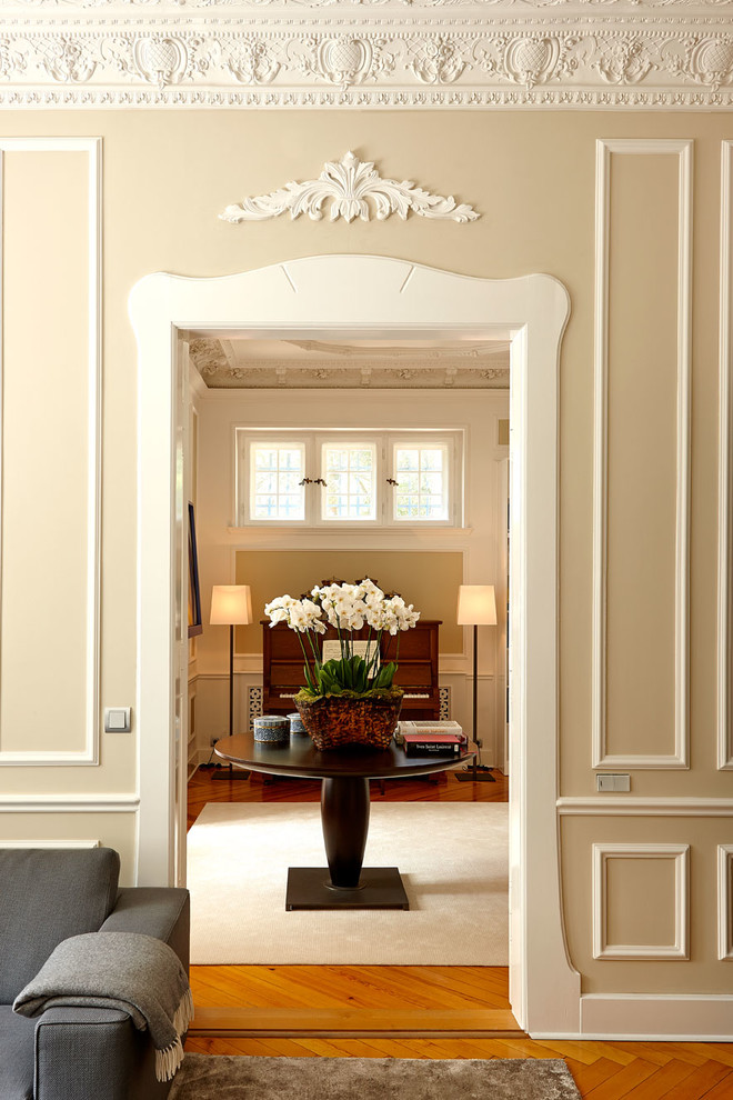 Aménagement d'un grand hall d'entrée classique avec un mur beige et un sol en bois brun.