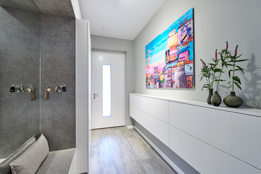 Photo of a medium sized contemporary front door in Hamburg with grey walls, medium hardwood flooring, a single front door, a white front door and brown floors.