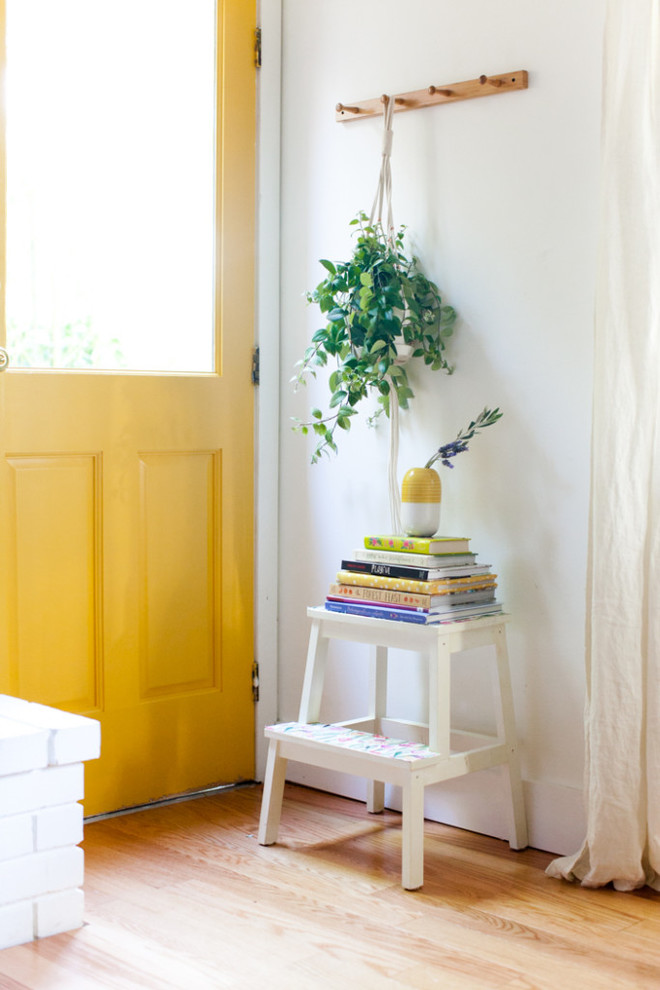 Esempio di un piccolo ingresso contemporaneo con pareti bianche, pavimento in legno massello medio, una porta singola, una porta gialla e pavimento marrone