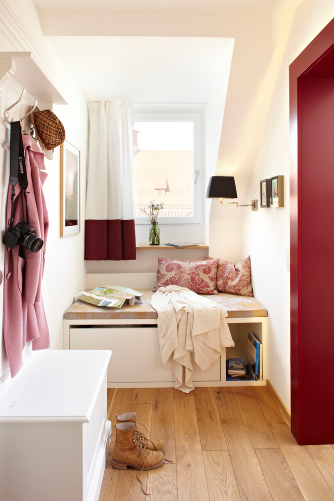 Exemple d'une entrée tendance de taille moyenne avec un vestiaire, un mur blanc et un sol en bois brun.