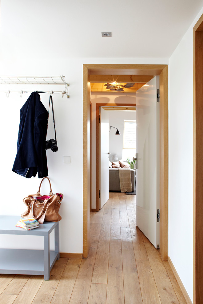 Cette image montre une entrée design de taille moyenne avec un vestiaire, un mur blanc et un sol en bois brun.