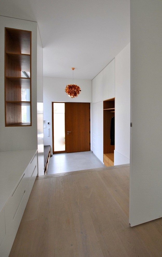 Mittelgroße Moderne Haustür mit weißer Wandfarbe, hellbrauner Holzhaustür, braunem Holzboden, Einzeltür und beigem Boden in Berlin