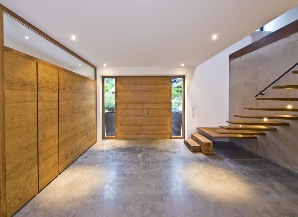 Großes Modernes Foyer mit Betonboden, Doppeltür, grauer Wandfarbe und hellbrauner Holzhaustür in Sonstige