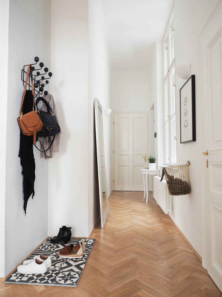 Imagen de entrada escandinava de tamaño medio con paredes blancas, suelo de madera en tonos medios y suelo marrón