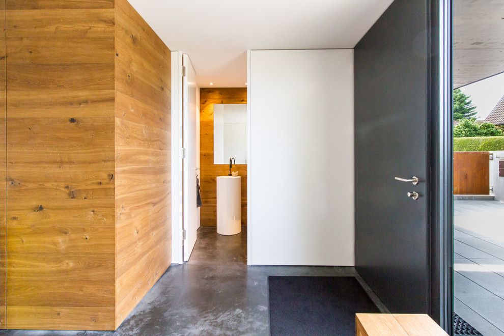 Kleine Moderne Haustür mit weißer Wandfarbe, Einzeltür, schwarzer Haustür und grauem Boden in München