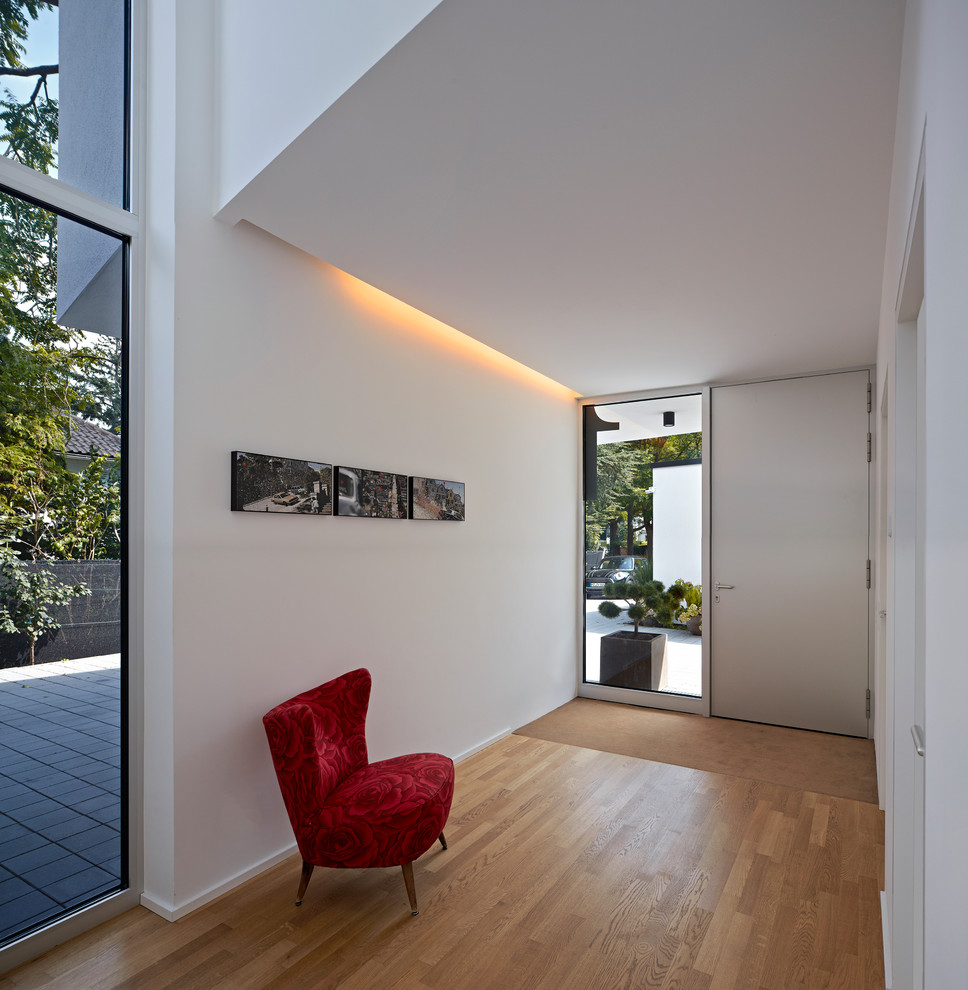Inspiration pour un hall d'entrée design avec un mur blanc, un sol en bois brun, une porte simple et une porte blanche.