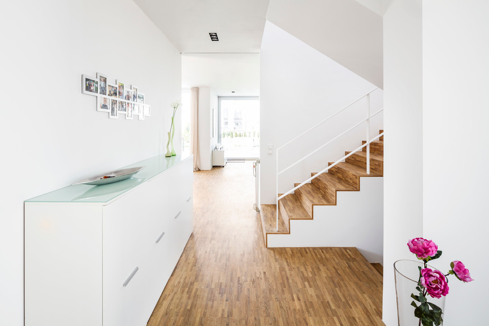 Entryway - contemporary medium tone wood floor entryway idea in Cologne with white walls