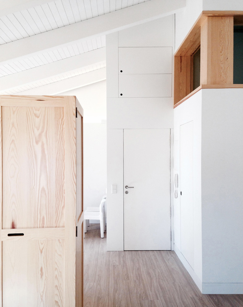 Idee per un corridoio contemporaneo di medie dimensioni con pareti bianche, pavimento in legno massello medio, una porta singola e una porta bianca
