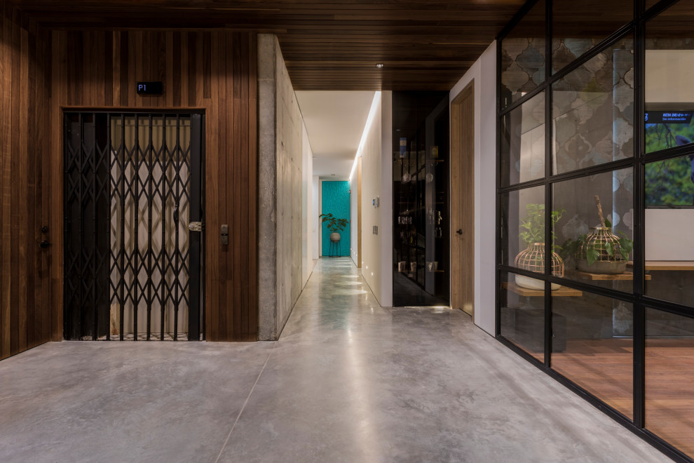 Inspiration pour une grande entrée design avec un couloir, un mur marron, sol en béton ciré, une porte coulissante, une porte noire et un sol gris.