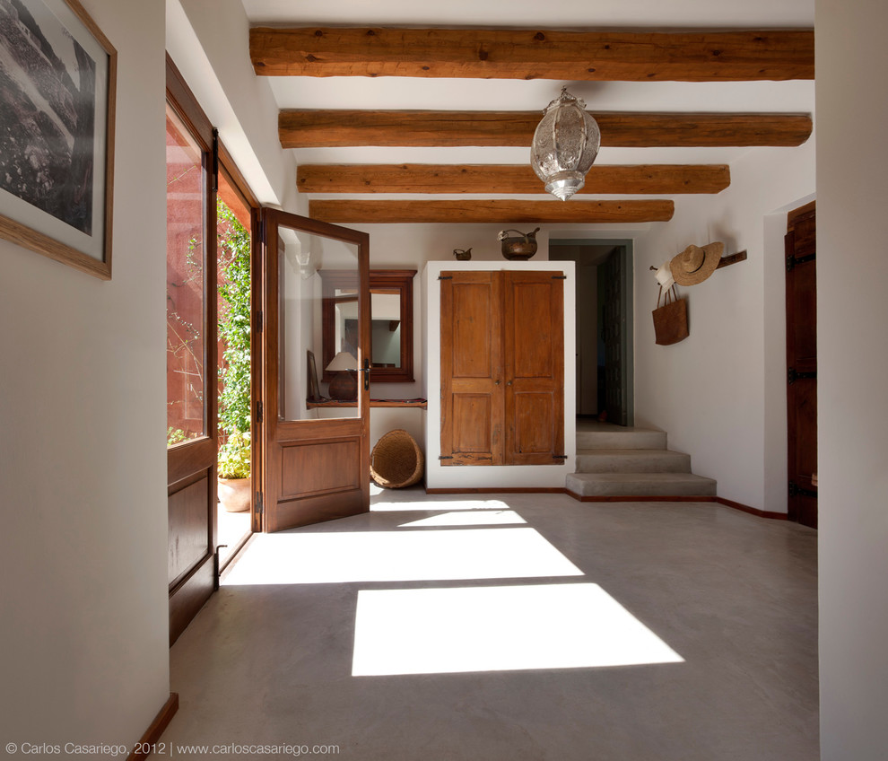 Mittelgroßes Mediterranes Foyer mit weißer Wandfarbe, Betonboden, Doppeltür und hellbrauner Holzhaustür in Sonstige