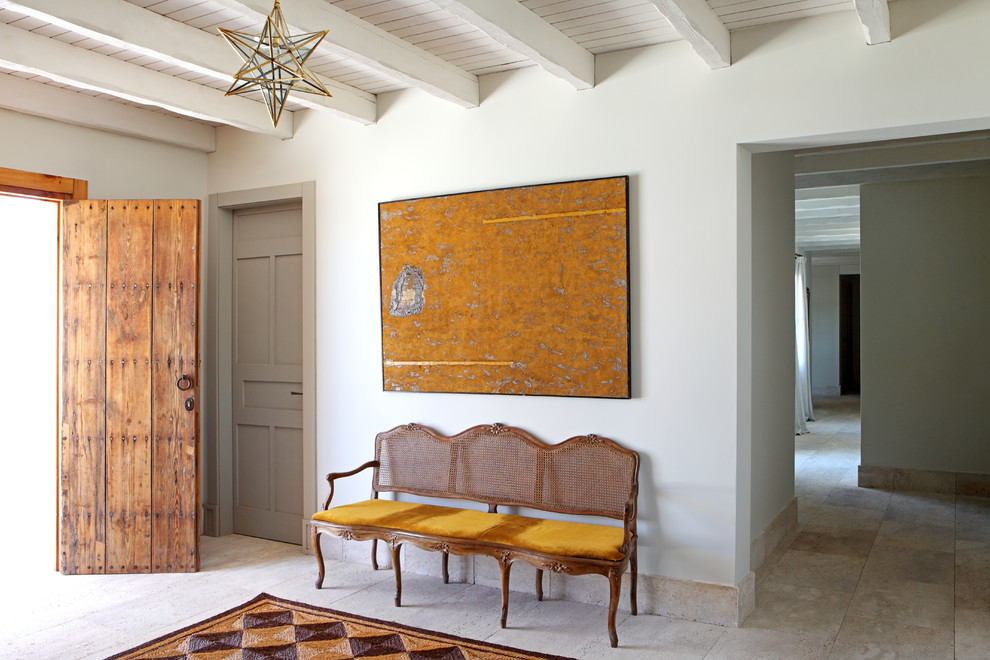 На фото: фойе в средиземноморском стиле с белыми стенами, входной дверью из дерева среднего тона и бежевым полом