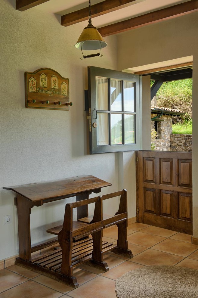 Kleine Rustikale Haustür mit Klöntür, hellbrauner Holzhaustür, weißer Wandfarbe, Terrakottaboden und rotem Boden in Sonstige