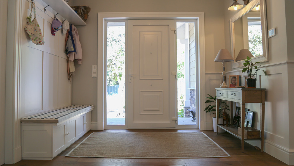 Idee per una porta d'ingresso classica di medie dimensioni con pareti beige, pavimento in legno massello medio, una porta singola, una porta bianca e pavimento marrone