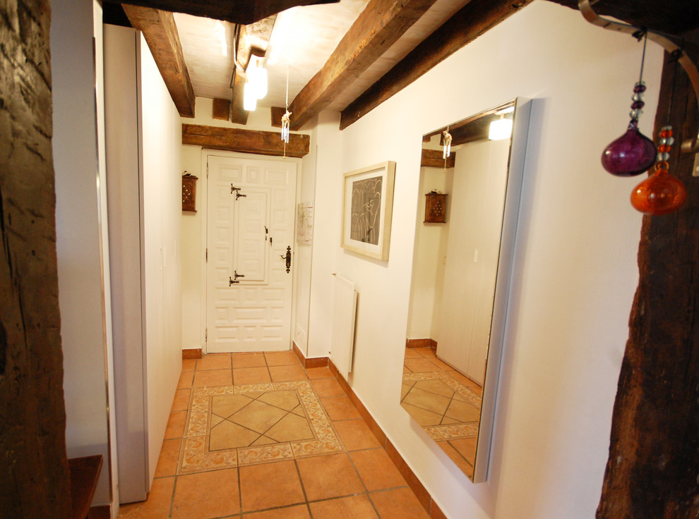 Esempio di una piccola porta d'ingresso country con pareti bianche, pavimento con piastrelle in ceramica, una porta singola, una porta bianca e pavimento marrone