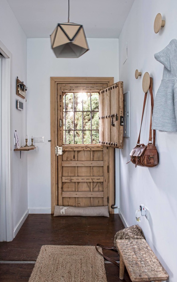 Diseño de hall bohemio con paredes blancas, suelo de madera oscura, puerta tipo holandesa y puerta de madera clara