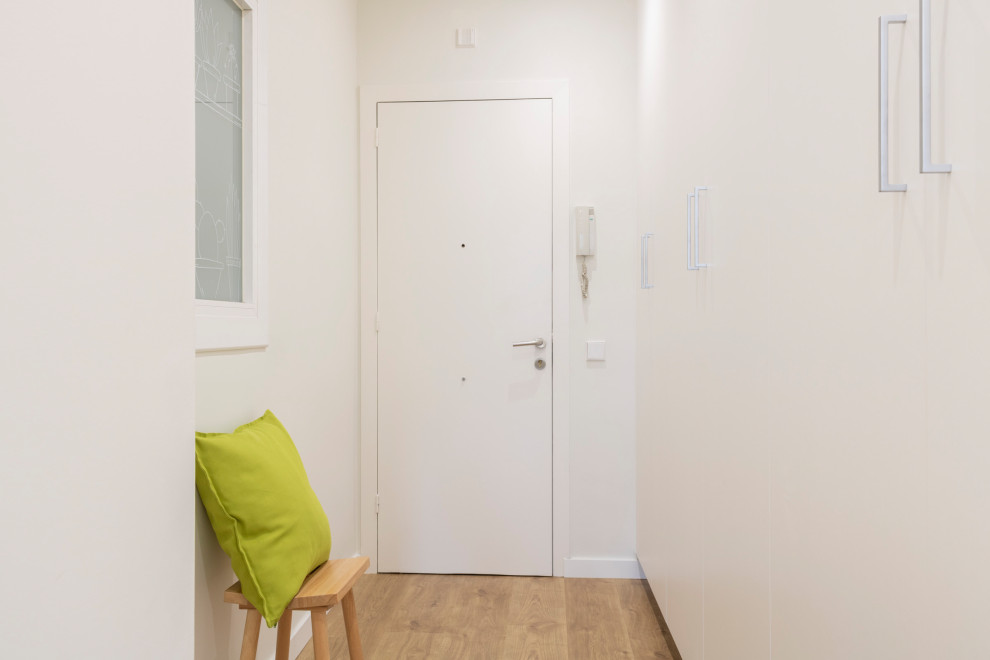 Idee per un ingresso o corridoio scandinavo di medie dimensioni con pareti bianche, parquet chiaro, una porta singola, una porta bianca e pavimento marrone