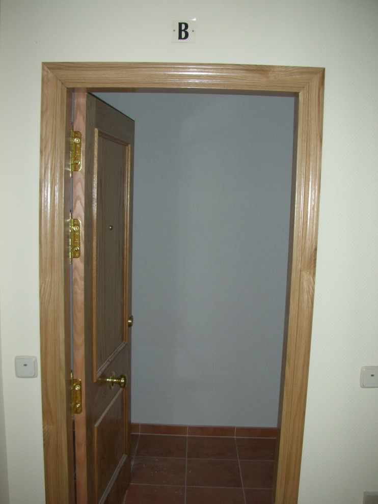 Modelo de puerta principal moderna pequeña con paredes amarillas, suelo de mármol, puerta simple, puerta de madera en tonos medios y suelo beige