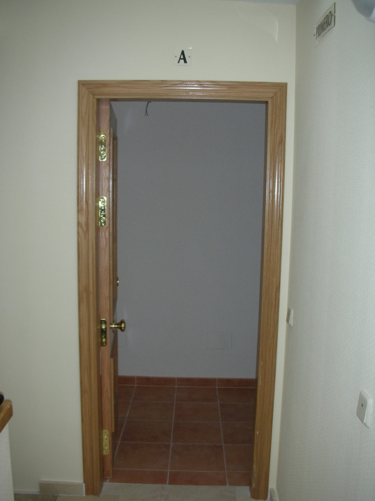 Foto på en liten funkis ingång och ytterdörr, med gula väggar, marmorgolv, en enkeldörr, mellanmörk trädörr och beiget golv