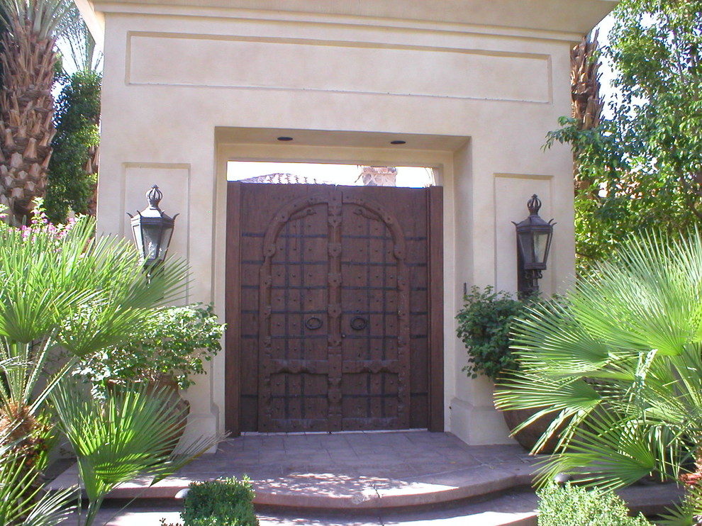 Cette image montre une porte d'entrée méditerranéenne avec un mur beige, une porte double et une porte marron.