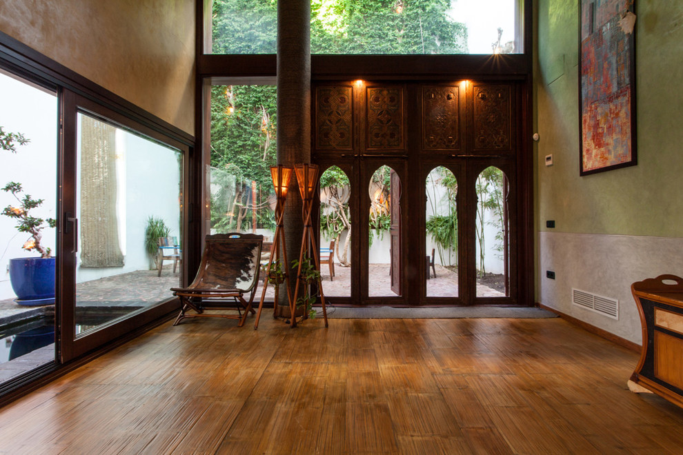 Foto de puerta principal tropical de tamaño medio con paredes verdes, puerta de madera oscura y suelo de madera en tonos medios