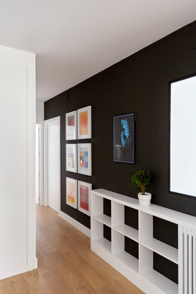 Mittelgroßes Modernes Foyer mit schwarzer Wandfarbe, hellem Holzboden und weißer Haustür in Madrid