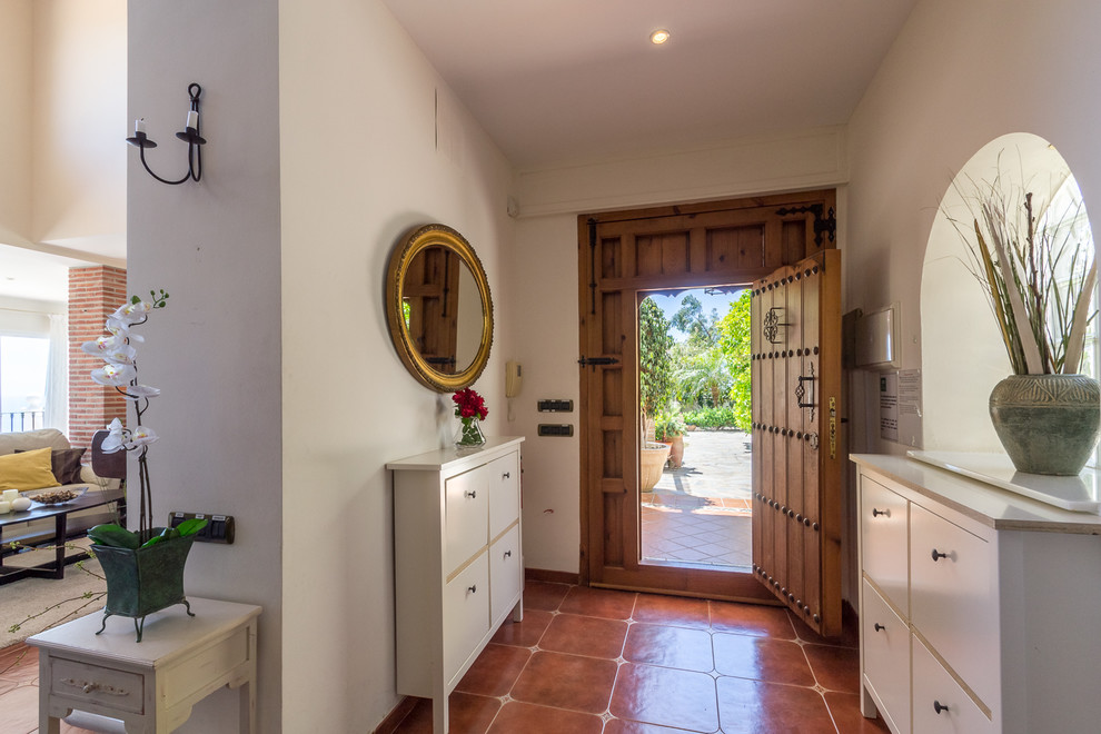 This is an example of a medium sized mediterranean front door in Other with beige walls, terracotta flooring, a stable front door, a medium wood front door and brown floors.