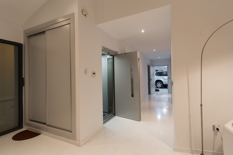Foto di un grande corridoio design con pareti bianche, pavimento in marmo, una porta singola, una porta in metallo e pavimento bianco