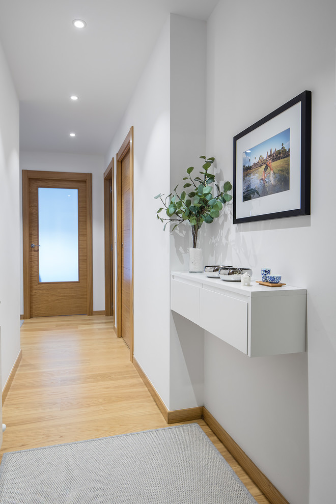 Imagen de hall bohemio pequeño con paredes blancas, suelo de madera clara, puerta simple, puerta de madera clara y suelo marrón