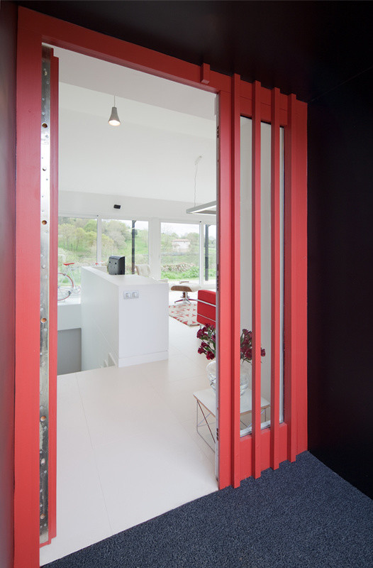 Ejemplo de entrada moderna con paredes negras, suelo de cemento, puerta doble y puerta roja
