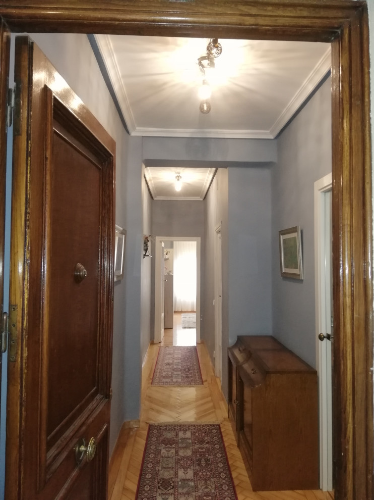 Diseño de puerta principal bohemia pequeña con paredes azules, suelo de madera clara, puerta de madera en tonos medios y suelo marrón