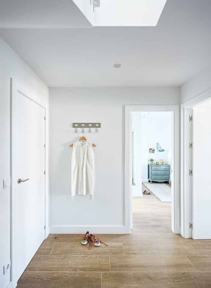 Ejemplo de hall marinero de tamaño medio con paredes blancas, suelo de baldosas de porcelana, puerta simple y puerta blanca