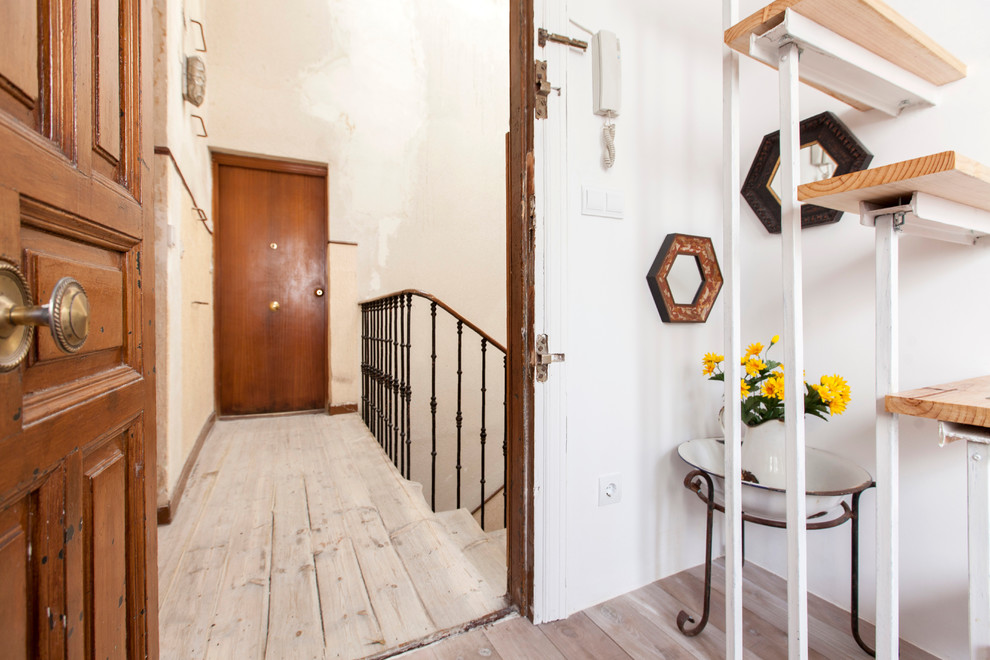 Foto de distribuidor bohemio pequeño con paredes blancas, suelo de madera en tonos medios, puerta simple y puerta de madera en tonos medios