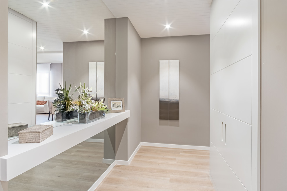 Imagen de hall minimalista grande con paredes grises, suelo laminado y puerta blanca