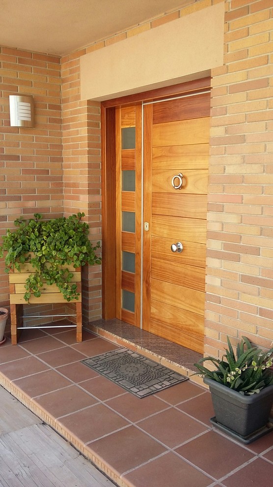 На фото: входная дверь среднего размера в стиле кантри с коричневыми стенами, одностворчатой входной дверью и входной дверью из дерева среднего тона