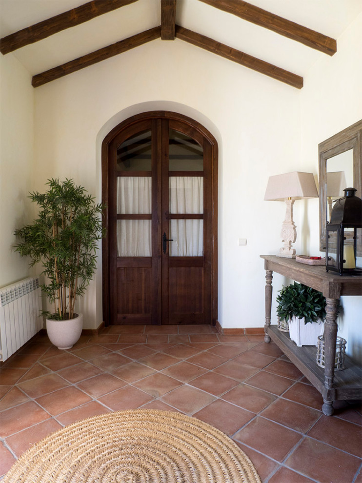 Ejemplo de vestíbulo campestre extra grande con paredes verdes, suelo de baldosas de terracota, puerta doble, puerta de madera oscura y suelo marrón