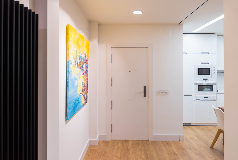Idee per un corridoio contemporaneo di medie dimensioni con pareti bianche, pavimento in legno massello medio, una porta singola e una porta bianca
