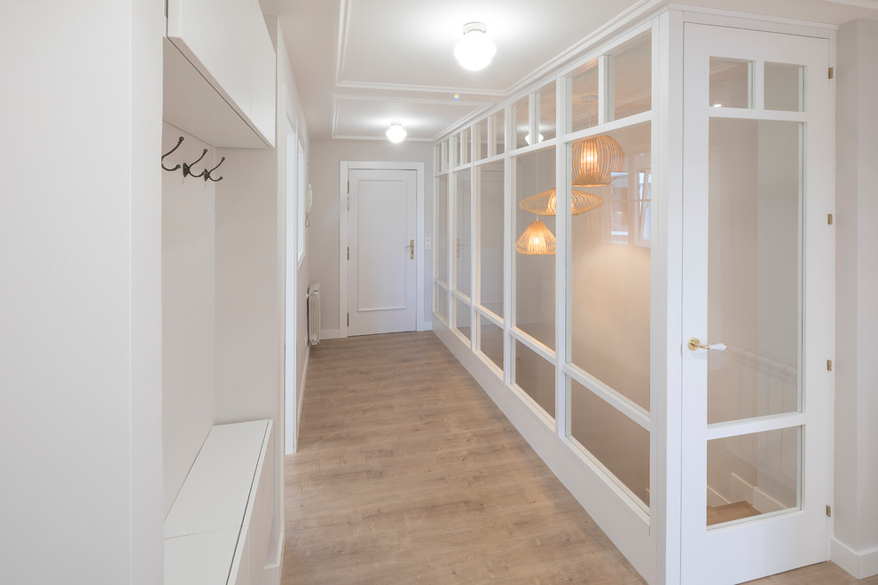 Стильный дизайн: узкая прихожая среднего размера в стиле неоклассика (современная классика) с серыми стенами, паркетным полом среднего тона, одностворчатой входной дверью, белой входной дверью и коричневым полом - последний тренд