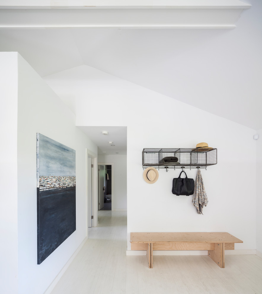 Imagen de entrada abovedada minimalista con paredes blancas, suelo de madera clara y suelo beige