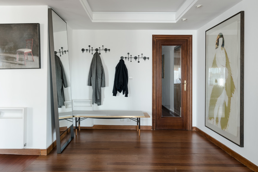 Modelo de vestíbulo minimalista grande con paredes blancas, suelo de madera oscura, puerta simple, puerta de madera oscura y suelo marrón