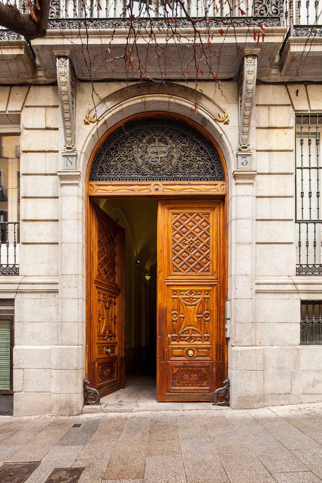 Diseño de puerta principal tradicional grande con paredes beige, puerta de madera en tonos medios, suelo de granito y puerta doble