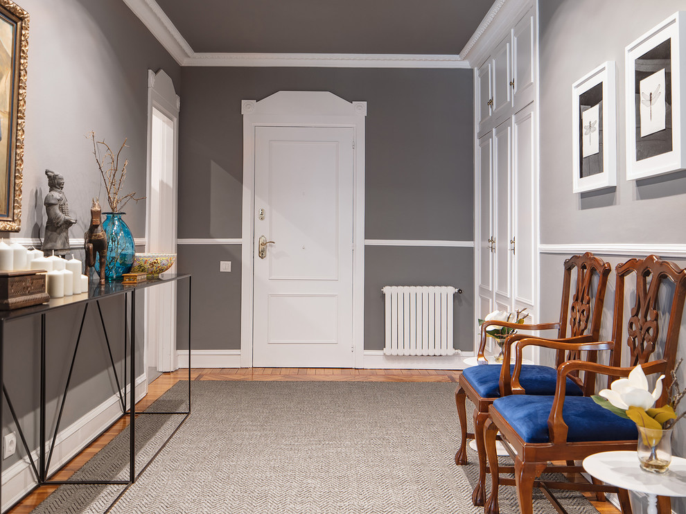Diseño de hall bohemio grande con paredes grises, suelo de madera clara, puerta simple, puerta blanca y suelo marrón