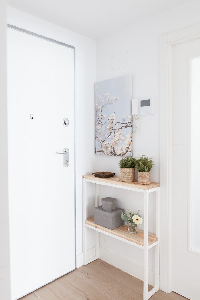 Пример оригинального дизайна: маленькая узкая прихожая в скандинавском стиле с белыми стенами, полом из керамической плитки, одностворчатой входной дверью, белой входной дверью и коричневым полом для на участке и в саду