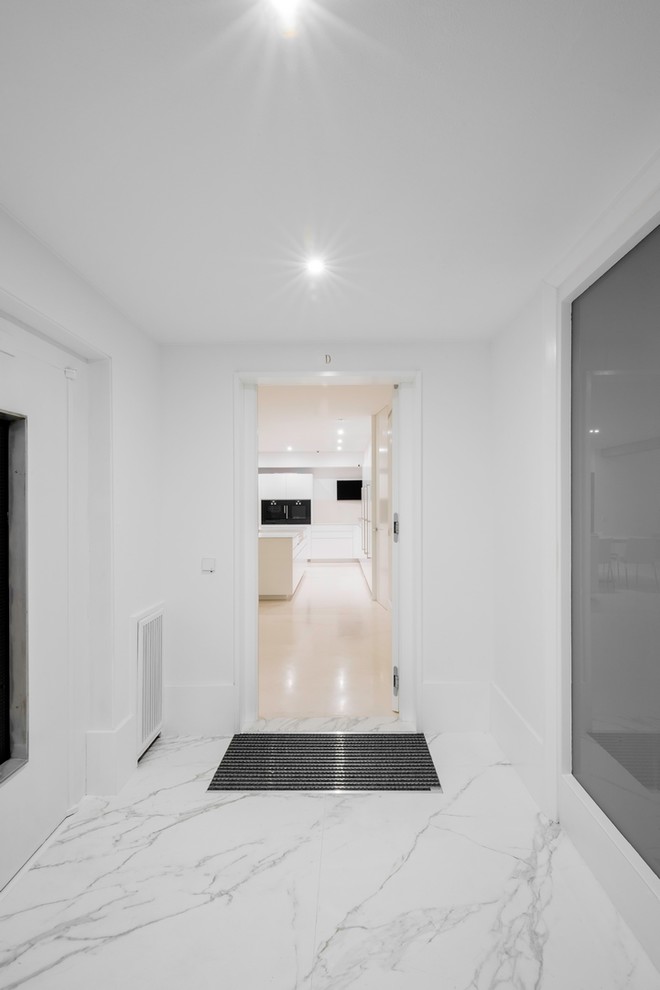 На фото: большое фойе в стиле модернизм с белыми стенами, мраморным полом, поворотной входной дверью, белой входной дверью и бежевым полом