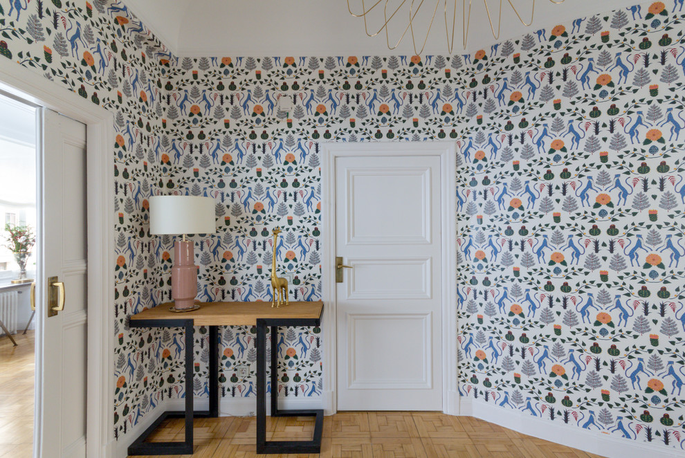 Exemple d'un hall d'entrée chic avec un mur multicolore, parquet clair, une porte simple, une porte blanche et un sol marron.