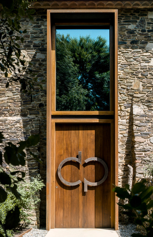 Imagen de puerta principal actual grande con paredes marrones, puerta simple y puerta de madera en tonos medios