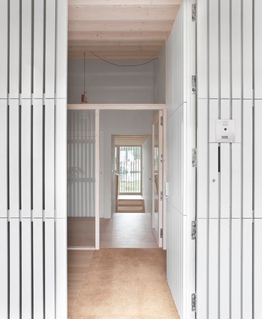Diseño de hall moderno de tamaño medio con paredes blancas, suelo de madera clara, puerta simple y puerta blanca
