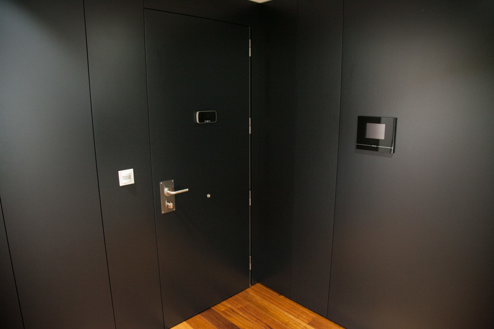 На фото: узкая прихожая среднего размера в стиле неоклассика (современная классика) с черными стенами, паркетным полом среднего тона, одностворчатой входной дверью и черной входной дверью с