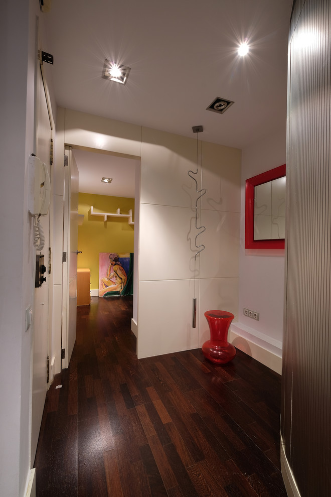 Esempio di un piccolo ingresso con vestibolo minimalista con pareti bianche, parquet scuro, una porta singola, una porta bianca e pavimento marrone