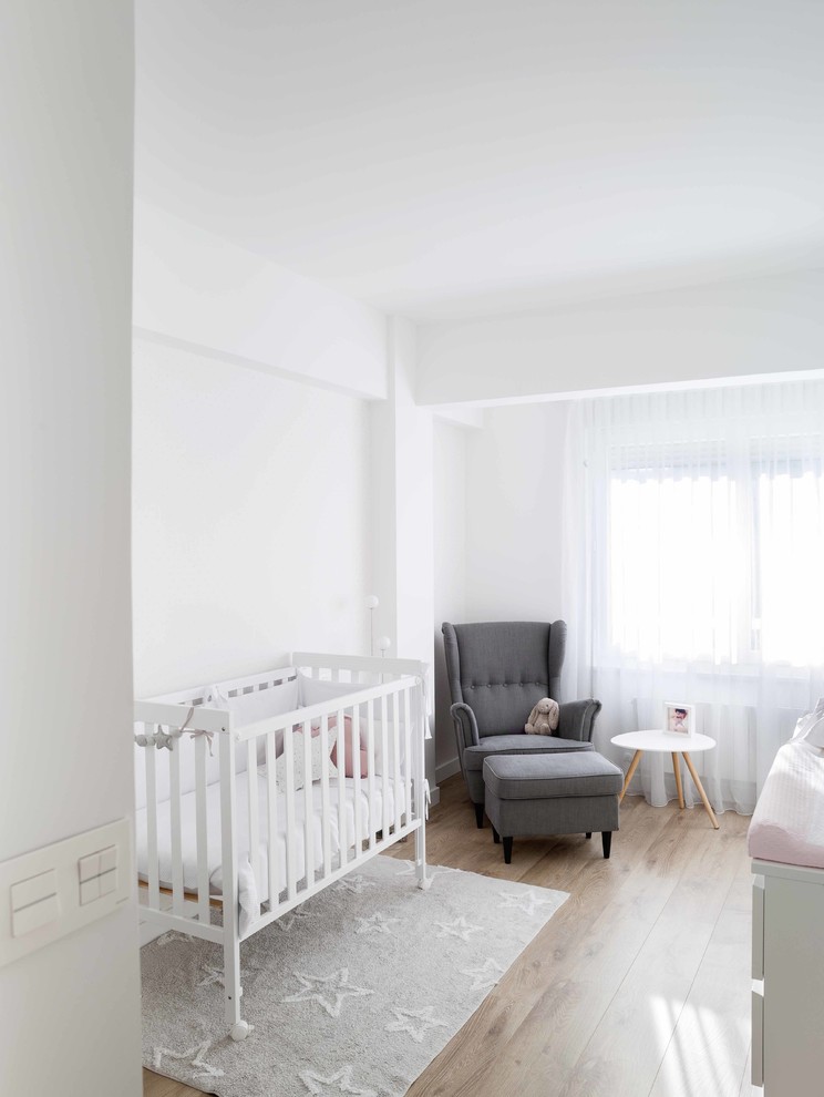 Exemple d'une chambre de bébé neutre scandinave de taille moyenne avec un mur blanc, sol en stratifié et un sol beige.